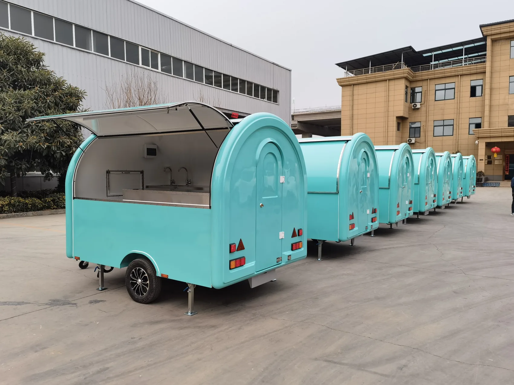 A row of turquoise mobile trailers outside a factory